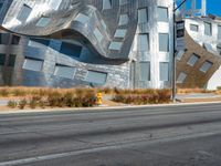 the street has a paved road next to a tall metal building with curvedly curved glass panels