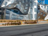 the street has a paved road next to a tall metal building with curvedly curved glass panels