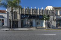 the store front of zara by a street with palm trees and building in the background