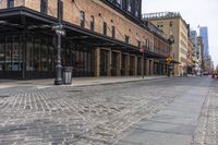 a brick sidewalk and street with buildings in the background of it and people walking around