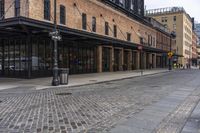 a brick sidewalk and street with buildings in the background of it and people walking around