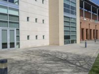 a sidewalk in front of a large building with lots of windows and doors in it