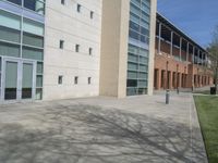 a sidewalk in front of a large building with lots of windows and doors in it