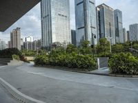 a couple of people riding skate boards near tall buildings on the street, in front of them is a walkway