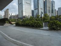 a couple of people riding skate boards near tall buildings on the street, in front of them is a walkway