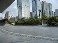 a couple of people riding skate boards near tall buildings on the street, in front of them is a walkway