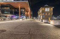 there is a paved walkway along the building's exterior with buildings in the background