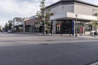 a car is driving by a shopping mall on the street corner, in an urban area