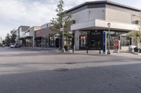 a car is driving by a shopping mall on the street corner, in an urban area