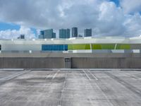 a large parking lot with some buildings behind it and clouds overhead above it in a city