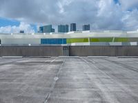 a large parking lot with some buildings behind it and clouds overhead above it in a city