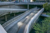 a river running under an overpass near a building with many tall buildings in the background