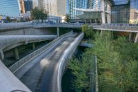 a river running under an overpass near a building with many tall buildings in the background