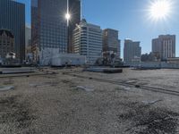 the truck is parked on the asphalt with the buildings in the background and a train going by