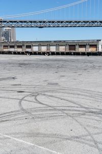 an empty parking lot with car tires painted on it and a boat dock in the back ground