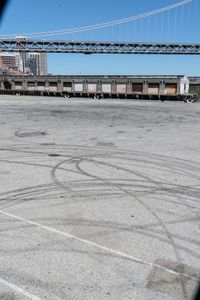 an empty parking lot with car tires painted on it and a boat dock in the back ground