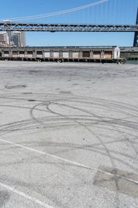 an empty parking lot with car tires painted on it and a boat dock in the back ground