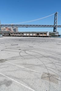 an empty parking lot with car tires painted on it and a boat dock in the back ground