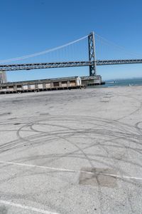 an empty parking lot with car tires painted on it and a boat dock in the back ground