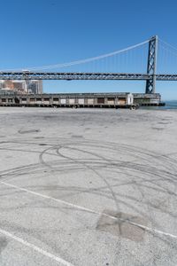 an empty parking lot with car tires painted on it and a boat dock in the back ground