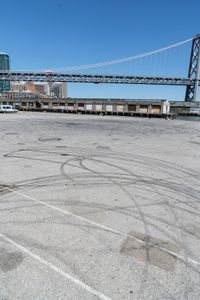 an empty parking lot with car tires painted on it and a boat dock in the back ground