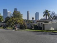 the view of a neighborhood with trees and buildings behind it is clear blue skies and a sun shines above