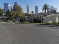 the view of a neighborhood with trees and buildings behind it is clear blue skies and a sun shines above