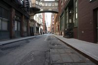 an alley way with people walking along and two cars in the street and buildings behind