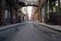an alley way with people walking along and two cars in the street and buildings behind