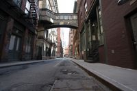 an alley way with people walking along and two cars in the street and buildings behind