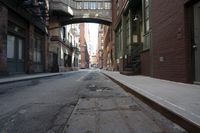 an alley way with people walking along and two cars in the street and buildings behind