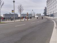 a group of people standing on the side of a road next to tall buildings and trees