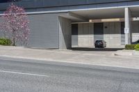 a black car sitting in a parking garage in front of a building next to the road