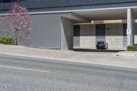 a black car sitting in a parking garage in front of a building next to the road