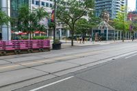 empty city street with lots of crates and people in the background, including some with umbrellas