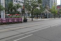 empty city street with lots of crates and people in the background, including some with umbrellas