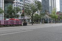 empty city street with lots of crates and people in the background, including some with umbrellas