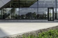 the sidewalk is surrounded by grass and plants on the concrete near the building's windows