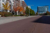 a sidewalk with a bus stop sign next to some buildings and trees with leaves growing on them