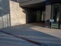 the sidewalk in front of a building with windows on the sides of the road and signs