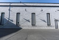 there is a white building with three large windows next to it and an alley way