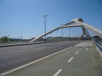 a truck driving across a bridge near a street corner near buildings and a bridge with many cables