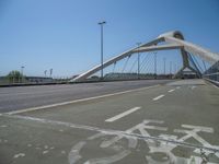 a truck driving across a bridge near a street corner near buildings and a bridge with many cables