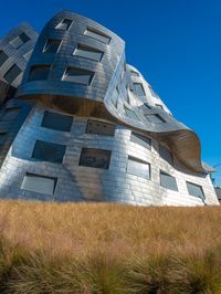 the building is made out of metal bricks and has lots of windows with some green grass