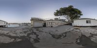 the panorama lens is shot in this fish eye image to the left is one of the buildings on the right is a small building that has white walls at the top of the building