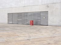 a red object sits on a wood floor near a white wall and large sliding garage