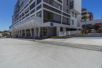 a large apartment building with parking spaces at the sidewalk next to it in front of a parking lot