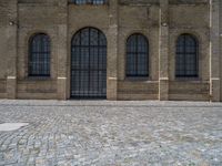 the sidewalk is paved with stones and has a bench in front of it, with no people inside