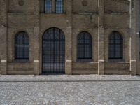 the sidewalk is paved with stones and has a bench in front of it, with no people inside