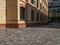 a sidewalk with chairs next to the brick building on the side, some have stairs and some buildings in the background